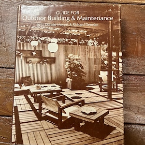 May include: A vintage book titled "Guide for Outdoor Building & Maintenance" by L. Donald Meyers & Richard Demske. The cover features a black and white photograph of a patio with wooden furniture and a pergola.