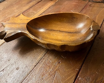 May include: A wooden pineapple-shaped bowl with a carved design. The bowl is made of a light brown wood and has a deep, oval-shaped interior. The bowl is resting on a wooden surface.