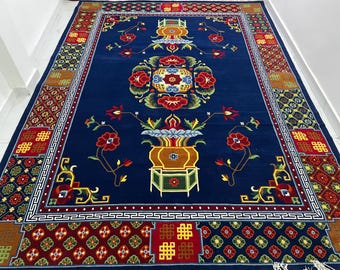 Puede incluir: Una alfombra azul rectangular grande con un intrincado diseño floral. La alfombra presenta un motivo central de jarrón con flores rojas, amarillas y verdes, rodeado por un borde detallado con patrones geométricos. La alfombra mide aproximadamente 244 cm por 305 cm.