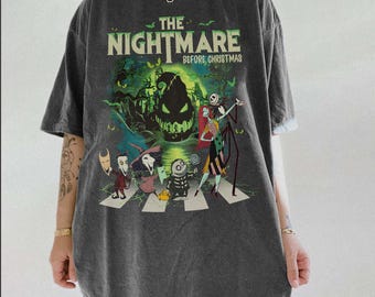 Puede incluir: Una camiseta de manga corta gris carbón con un estampado gráfico de los personajes de Pesadilla antes de Navidad, incluidos Jack Skellington, Sally y Oogie Boogie, caminando por un paso de cebra con detalles en verde y murciélagos.
