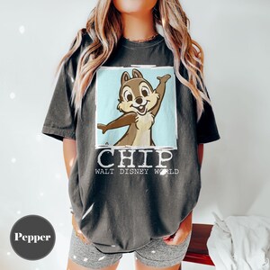 May include: Dark grey t-shirt featuring Chip from Disney's Chip 'n Dale Rescue Rangers. The graphic shows Chip with arms outstretched against a light blue background. The word "CHIP" and "WALT DISNEY WORLD" are printed below the image.