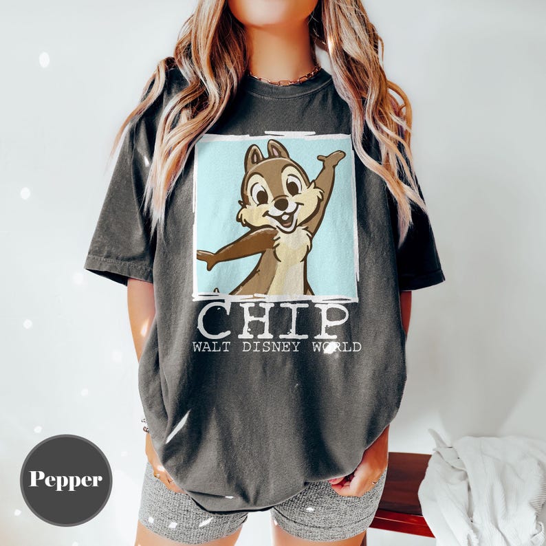 May include: Dark grey t-shirt featuring Chip from Disney's Chip 'n Dale Rescue Rangers. The graphic shows Chip with arms outstretched against a light blue background. The word "CHIP" and "WALT DISNEY WORLD" are printed below the image.