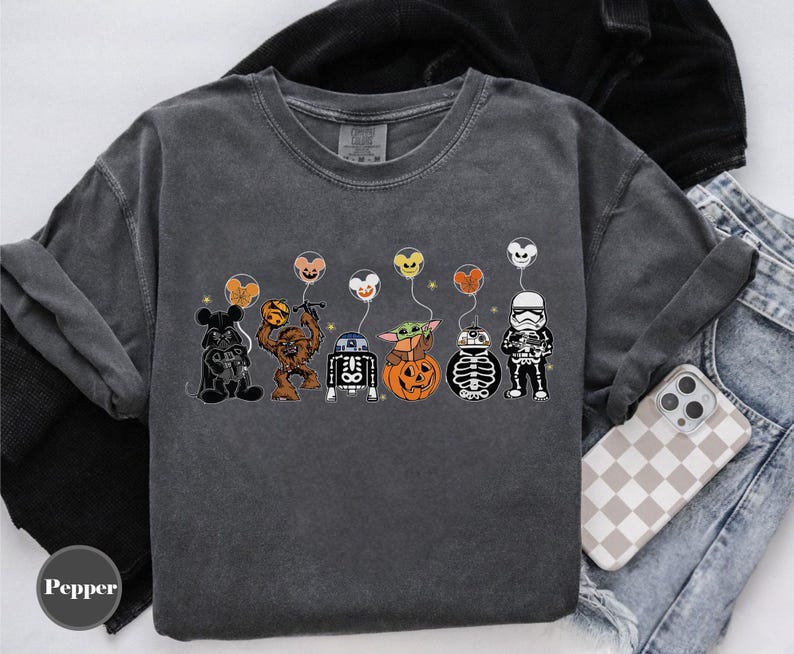 Puede incluir: Camiseta gris oscuro con personajes de dibujos animados disfrazados para Halloween. Los personajes incluyen Mickey Mouse, Chewbacca, R2-D2, Baby Yoda y un Stormtrooper, cada uno sosteniendo un globo. La palabra "Pepper" est&aacute; en la esquina inferior izquierda.