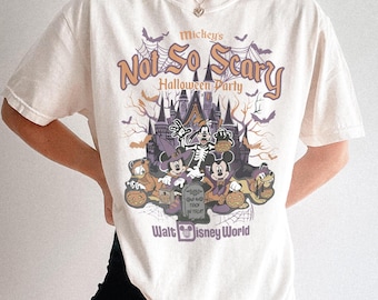 Puede incluir: Una camiseta de manga corta color crema con un estampado gráfico de Mickey's Not So Scary Halloween Party en Walt Disney World. El diseño incluye personajes de dibujos animados con disfraces, un castillo embrujado, calabazas y murciélagos.