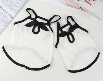 May include: Two white sleeveless tops with black trim and a black bow at the neckline.