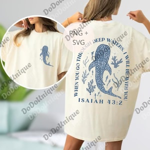 Pode incluir: Camiseta creme com design de baleia azul. A frente tem uma baleia pequena, a parte de trás uma maior com o texto "WHEN YOU GO THROUGH DEEP WATERS, I WILL BE WITH YOU. ISAIAH 43:2". Mangas curtas, corte largo.