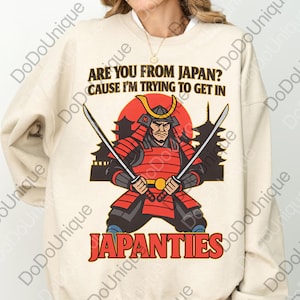 May include: A beige sweatshirt with a graphic of a samurai warrior holding two swords. The text "ARE YOU FROM JAPAN? CAUSE I'M TRYING TO GET IN JAPANTIES" is printed in black and red.