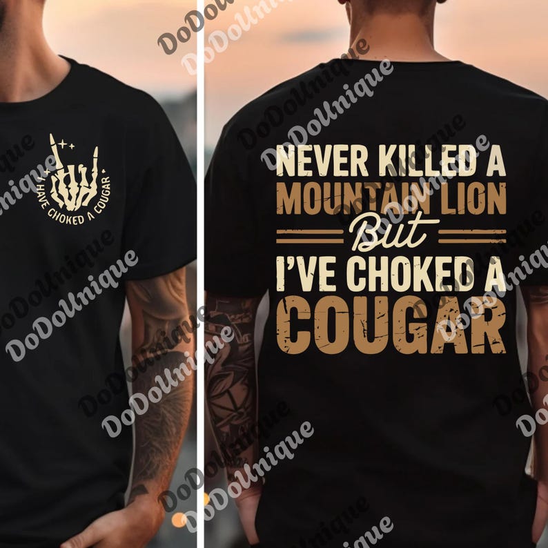 a black t-shirt with a graphic design on the back. The design includes text and a graphic of a cougar, which is a type of wild cat. The text on the t-shirt reads "NEVER KILLED A MOUNTAIN LION BUT I'VE CHOKED A COUGAR".