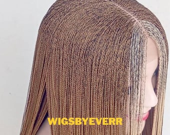 May include: A long, braided wig with a mix of brown and blonde strands. The wig features a center part and a natural-looking hairline. The text "WIGSBYEVERR" is visible at the bottom of the image.