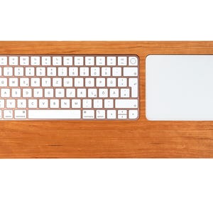 Könnte beinhalten: Ein Holz-Tastatur- und Trackpad-Kombination mit einer weißen Tastatur- und Trackpad-Oberfläche. Die Tastatur hat ein Standardlayout mit in Englisch beschrifteten Tasten.