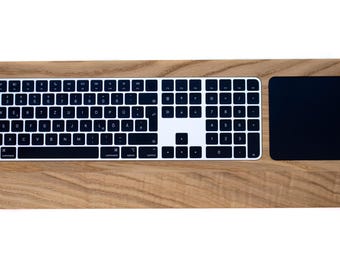 Puede incluir: Un teclado de computadora rectangular con acabado de veta de madera, con teclas negras y letras blancas en disposición QWERTZ, un teclado numérico blanco y un panel táctil rectangular negro integrado en el lado derecho.