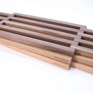 Puede incluir: Listones de madera apilados con un patrón de rejilla, hechos de madera clara y oscura. Los listones tienen el texto "echt holz ideen.de" grabado.