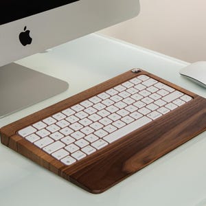 May include: A white wireless keyboard with a walnut wood base. The keyboard is angled upwards and has a white mouse next to it.