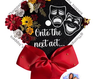 Pode incluir: Tampo de formatura preto decorado com flores de papel vermelhas, amarelas e brancas, com detalhes de borboletas. O tampo apresenta o texto "Onto the next act..." e máscaras de comédia/tragédia. Uma grande fita vermelha com detalhes dourados está presa.