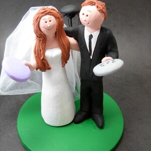 May include: A wedding cake topper featuring a bride and groom figurine. The bride is wearing a white dress and a veil. The groom is wearing a black suit and a tie. The cake topper is on a green base.