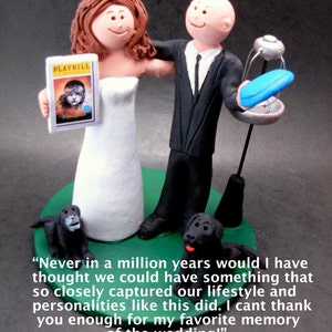 May include: A wedding cake topper featuring a bride and groom in a whimsical style. The bride is holding a Playbill for the musical "The Music Man". The groom is holding a blue frisbee. The cake topper is on a green base with two black dogs.
