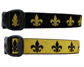 Könnte beinhalten: Zwei Hundehalsbänder mit schwarzen und goldenen Fleur-de-lis-Designs. Das obere Halsband hat einen schwarzen Hintergrund mit goldenen Fleur-de-lis. Das untere Halsband hat einen goldenen Hintergrund mit schwarzen Fleur-de-lis.