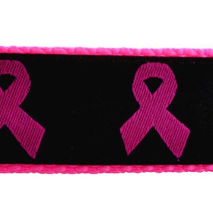 Op de afbeelding: Zwarte hondenriem met roze lintpatroon. De riem heeft een zwarte gesp en een roze rand.