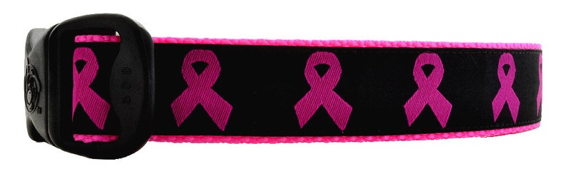 Op de afbeelding: Zwarte hondenriem met roze lintpatroon. De riem heeft een zwarte gesp en een roze rand.