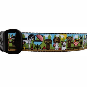 May include: A colorful dog-themed collar with a black buckle. The collar features a repeating pattern of dogs enjoying a picnic with a grill, watermelon, and other picnic foods.