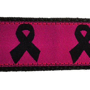 Op de afbeelding: Roze hondenriem met zwarte lintontwerpen. De riem heeft een zwarte gesp.