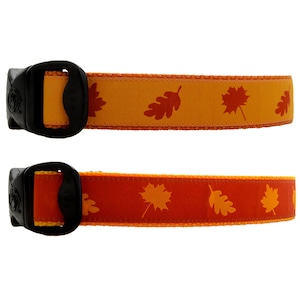 May include: Two dog collars with a fall leaf pattern. The top collar is orange with brown leaves. The bottom collar is red with orange leaves.