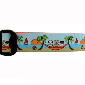 May include: A blue and tan dog collar with a colorful print of dogs in a hammock on a beach with palm trees and a sailboat.