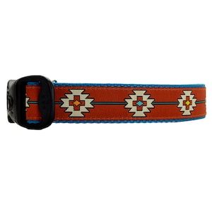 May include: A red dog collar with a blue border and a geometric pattern in orange, yellow, and white.