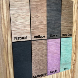 May include: A wood sample board with different wood finishes. The finishes are: Natural, Antique, Ebony, Dark Oak, Black, Mahogany, Purple, and Teal.