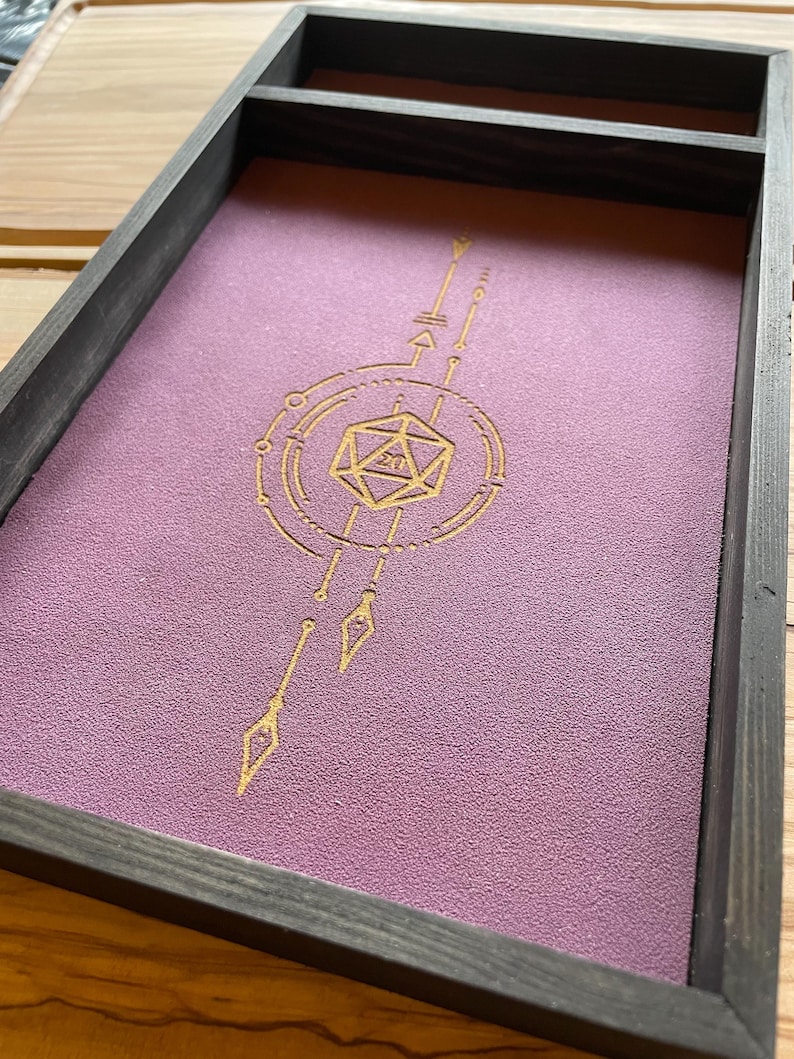 May include: A wooden dice tray with a purple felt lining and a gold geometric design featuring a 20-sided die in the center.