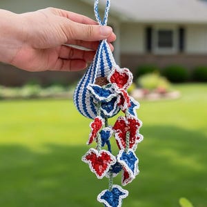 Puede incluir: Adorno de ganchillo hecho a mano con forma de lágrima a rayas azules y blancas y detalles de hojas rojas y azules. El adorno tiene un lazo para colgar. El esquema de color es patriótico.