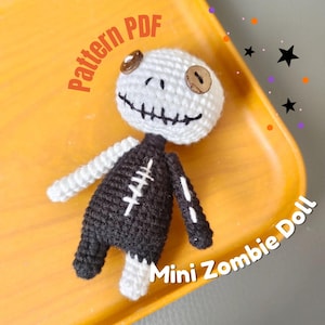 May include: A handmade crochet mini zombie doll with a white head and black body. The doll has button eyes and a stitched mouth. The text "Pattern PDF" and "Mini Zombie Doll" are visible.
