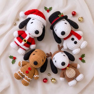 Peut inclure: Quatre poupées chiens en crochet disposées en cercle. L'une porte un costume et un bonnet de Père Noël rouges, une autre un haut-de-forme noir et une écharpe rouge, une ressemble à un bonhomme en pain d'épices, et une porte des bois de renne.