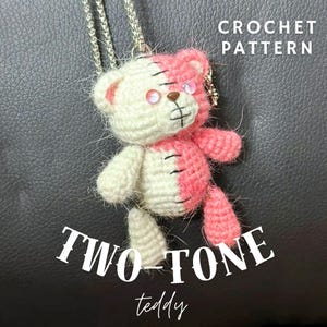 May include: A two-tone crochet teddy bear pendant on a silver chain. The bear is half white and half pink, with black stitched details and rhinestone eyes. The image includes the text "CROCHET PATTERN" and "TWO-TONE teddy".