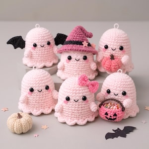 Può includere: Sei figure di fantasmi all'uncinetto rosa chiaro con occhi neri e guance rosee. Un fantasma ha ali nere, uno indossa un cappello da strega rosa, uno tiene una piccola zucca rosa, uno ha un fiocco rosa e uno tiene un secchiello a forma di zucca.
