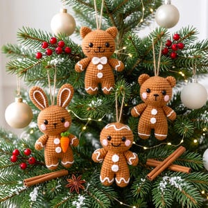 Puede incluir: Cuatro adornos de ganchillo colgados en un árbol de Navidad: un gato marrón, un conejo con una zanahoria, un hombre de jengibre y un osito de peluche. Cada figura tiene detalles blancos, ojos negros y mejillas rosadas, colgados con cuerda.