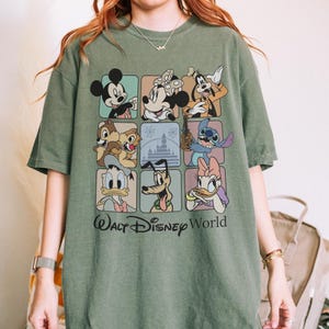 May include: Green t-shirt featuring a grid of Disney characters including Mickey Mouse, Minnie Mouse, Goofy, Chip and Dale, Stitch, Donald Duck, Pluto, and Daisy Duck. The words "Walt Disney World" are printed below the grid.