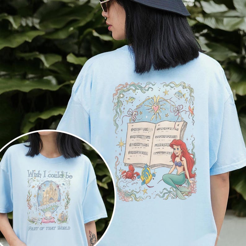 May include: Pale blue t-shirt with a graphic of Ariel from The Little Mermaid, musical notes and the text "Wish I could be, Part of that world." The back of the shirt has a larger illustration of Ariel with musical notes.