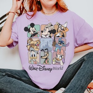 May include: A light purple t-shirt featuring a grid of Disney characters including Mickey Mouse, Minnie Mouse, Goofy, Chip and Dale, Stitch, Donald Duck, Pluto, and Daisy Duck. The words "Walt Disney World" are printed below the grid.