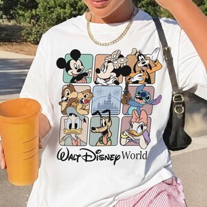 May include: White t-shirt featuring a colorful grid of Disney characters including Mickey Mouse, Minnie Mouse, Goofy, Chip and Dale, Stitch, Donald Duck, Pluto, and Daisy Duck. The words "Walt Disney World" are printed below the grid.