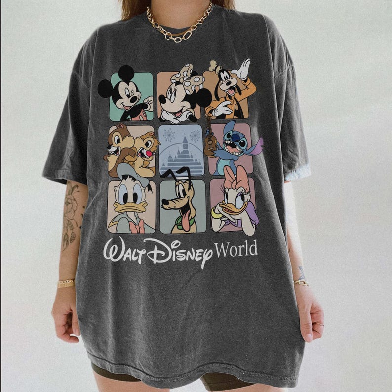 May include: Dark gray t-shirt featuring a colorful grid of Disney characters including Mickey Mouse, Minnie Mouse, and Goofy. The shirt has the text "Walt Disney World" in a script font.