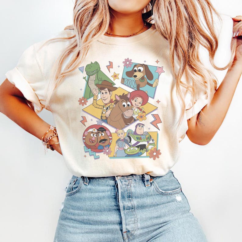 Pode incluir: Camiseta creme com um gr&aacute;fico colorido de personagens do filme de anima&ccedil;&atilde;o Toy Story. O design inclui Woody, Buzz Lightyear e outros personagens em um estilo retr&ocirc;, com flores.
