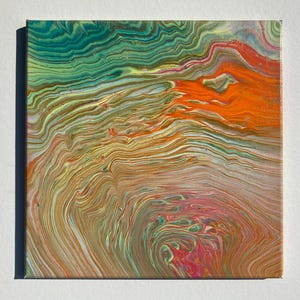 May include: A square canvas featuring an abstract acrylic pour painting with fluid, swirling lines. The composition displays a vibrant color palette of deep teal, bright orange, golden yellow, and soft pink, creating a marbled, layered effect.