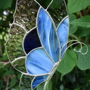 May include: A stained glass butterfly garden stake with blue, dark blue, and green glass pieces. The butterfly is attached to a silver metal stake.
