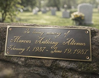 May include: A rectangular bronze plaque with gold lettering, mounted on a stone wall. The inscription reads "In loving memory of Marcus Anthony Altemus February 1, 1987 - June 19, 1987". The background shows a cemetery.