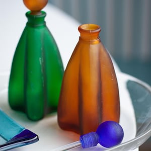 Encantadores recipientes para fragancias con tapones de vidrio: frascos de perfume vintage coleccionables en verde esmeralda y marrón.