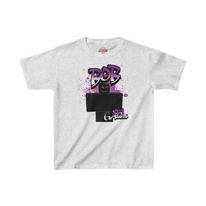 May include: A gray t-shirt with a purple and black graphic of a Roblox character with the text "BOB G4EL" on it.