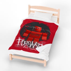May include: A red and white comforter featuring a red block figure with a smiling face, set against a black background. The text "FORSAKEN" and "ANY NAME" are written in white. The comforter is on a wooden bed frame.