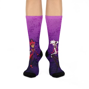 Puede incluir: Un par de calcetines morados con un aspecto descolorido y texturado. Los calcetines presentan un estampado gráfico de dos personajes de dibujos animados, uno rojo y otro blanco, sobre un fondo morado.