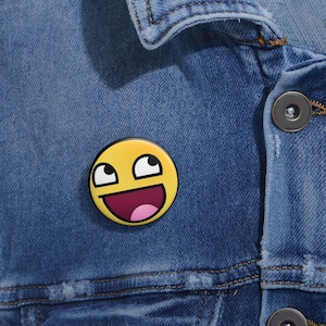 Puede incluir: Un botón amarillo con una cara sonriente con ojos grandes y la boca abierta. La cara es un meme de internet popular.